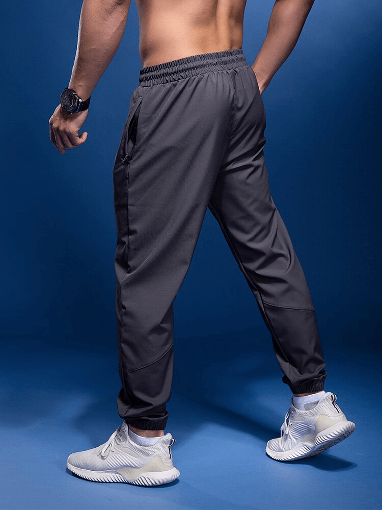 Back view of male running joggers with elastic waist and zipper pockets, perfect for active wear. Polyester-spandex blend for flexibility.